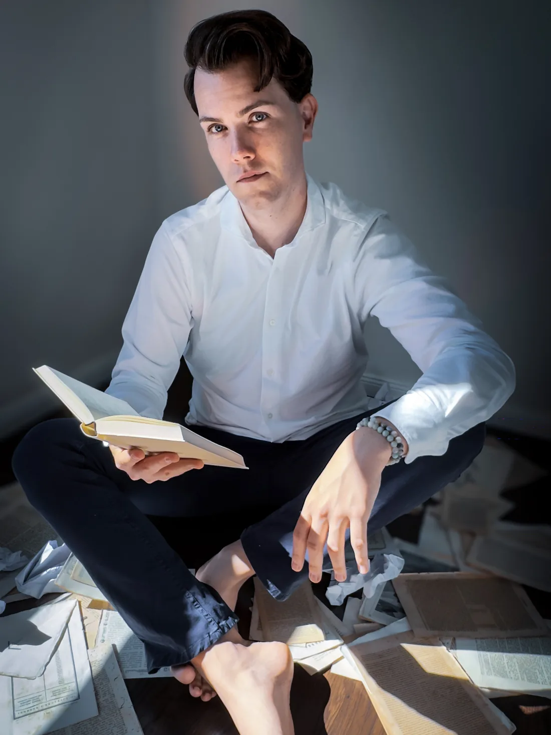 Mika Maria zwischen aufgeschlagenen Büchern und losen Blättern, ein Buch in der Hand